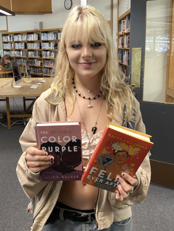 Isabelle Jolson holds up two banned books: The Color Purple by Alice Walker and Felix Ever After by Kacen Callender.